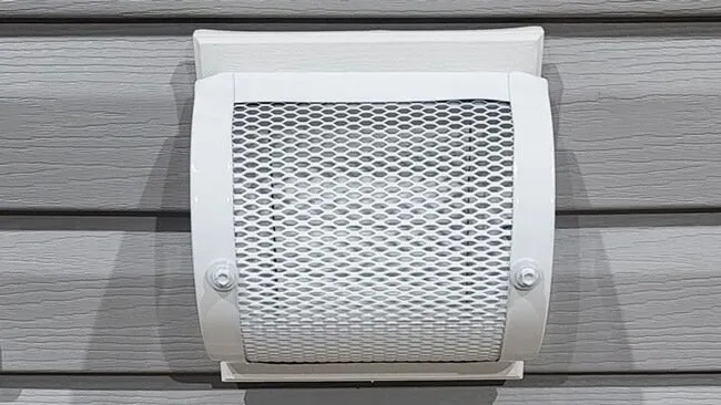 Mesh guard installed over a bathroom exhaust vent on siding