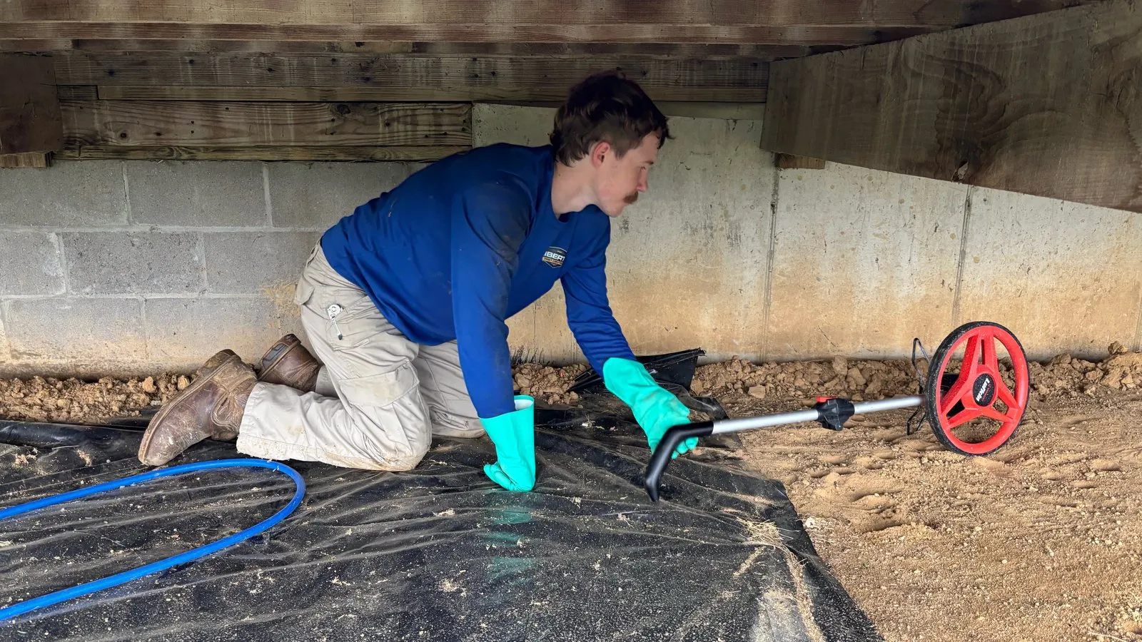 Liberty Service Specialist in a crawlspace measuring with a measuring wheel