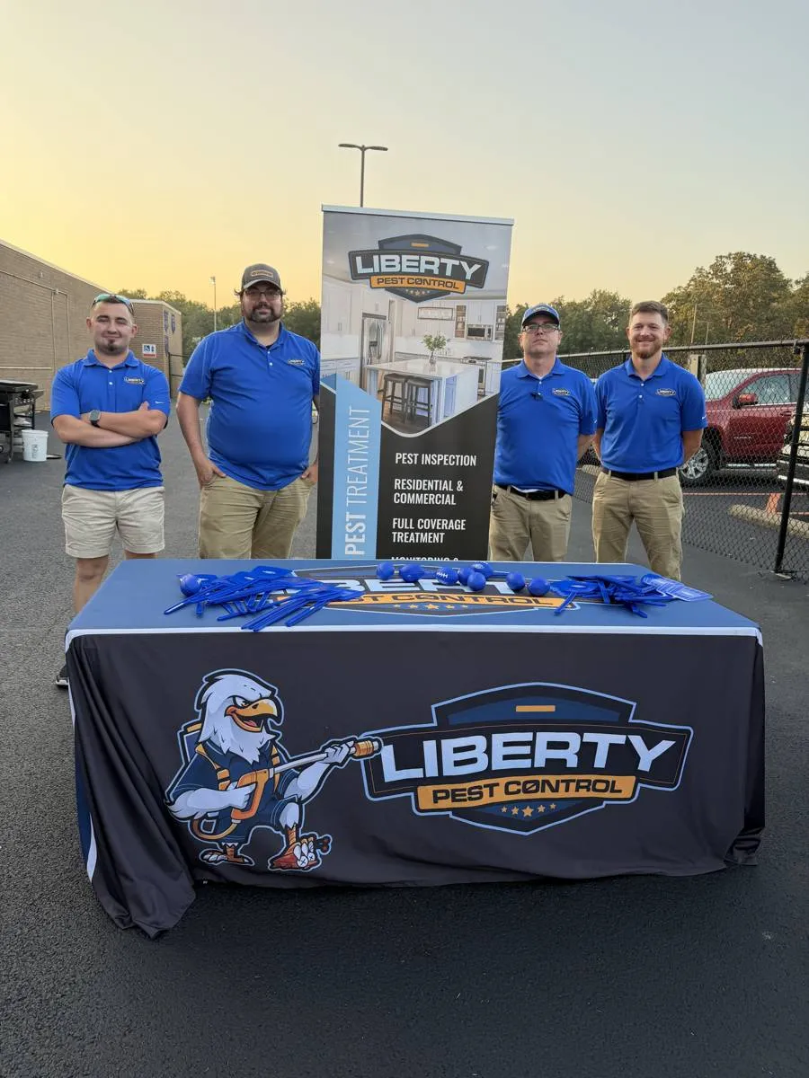 Four Liberty Pest Control team members at a community event booth
