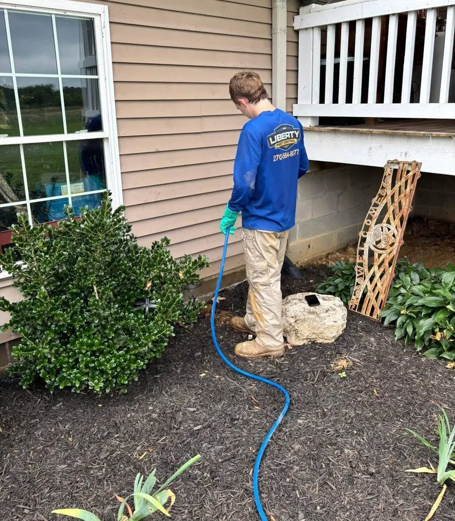 Liberty Service Specialist treating foundation beds outside a home