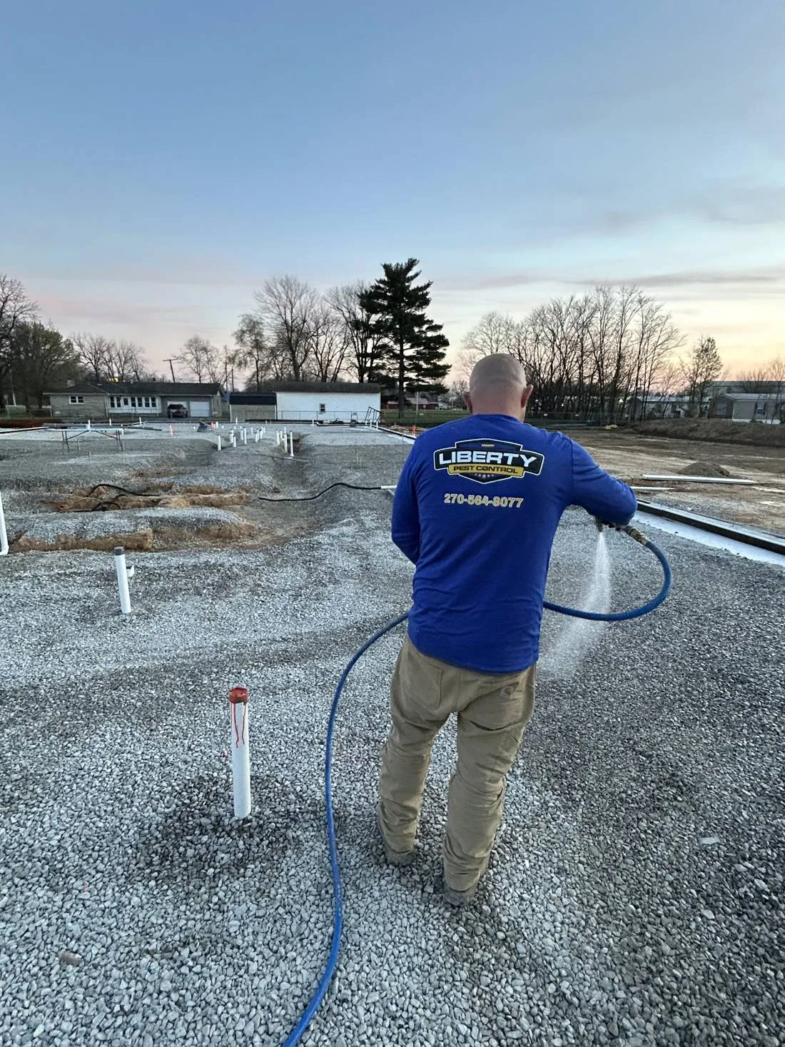 Liberty Service Specialist spraying the ground at a pre-construction slab site