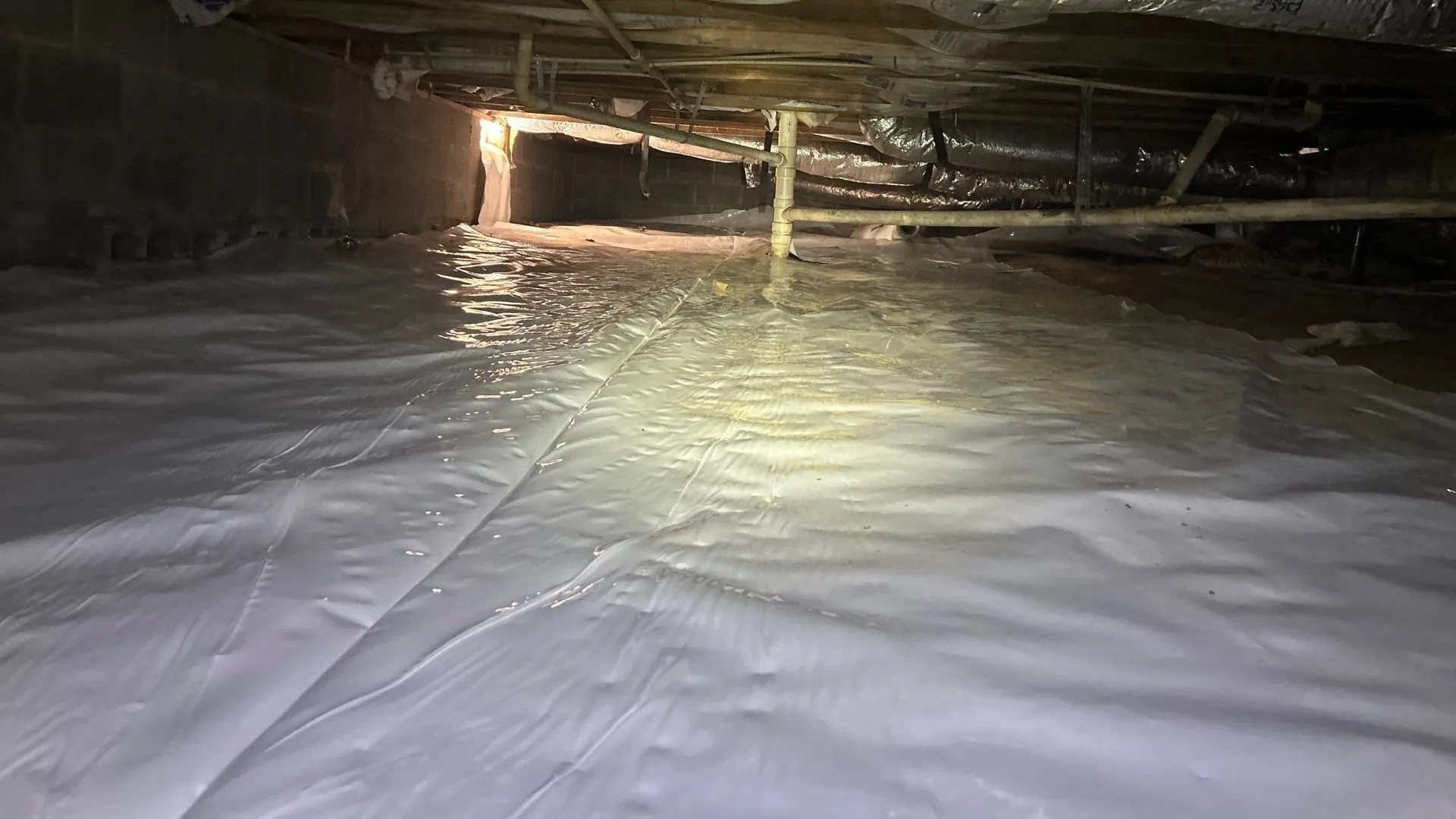 White vapor barrier covering the ground of a crawlspace