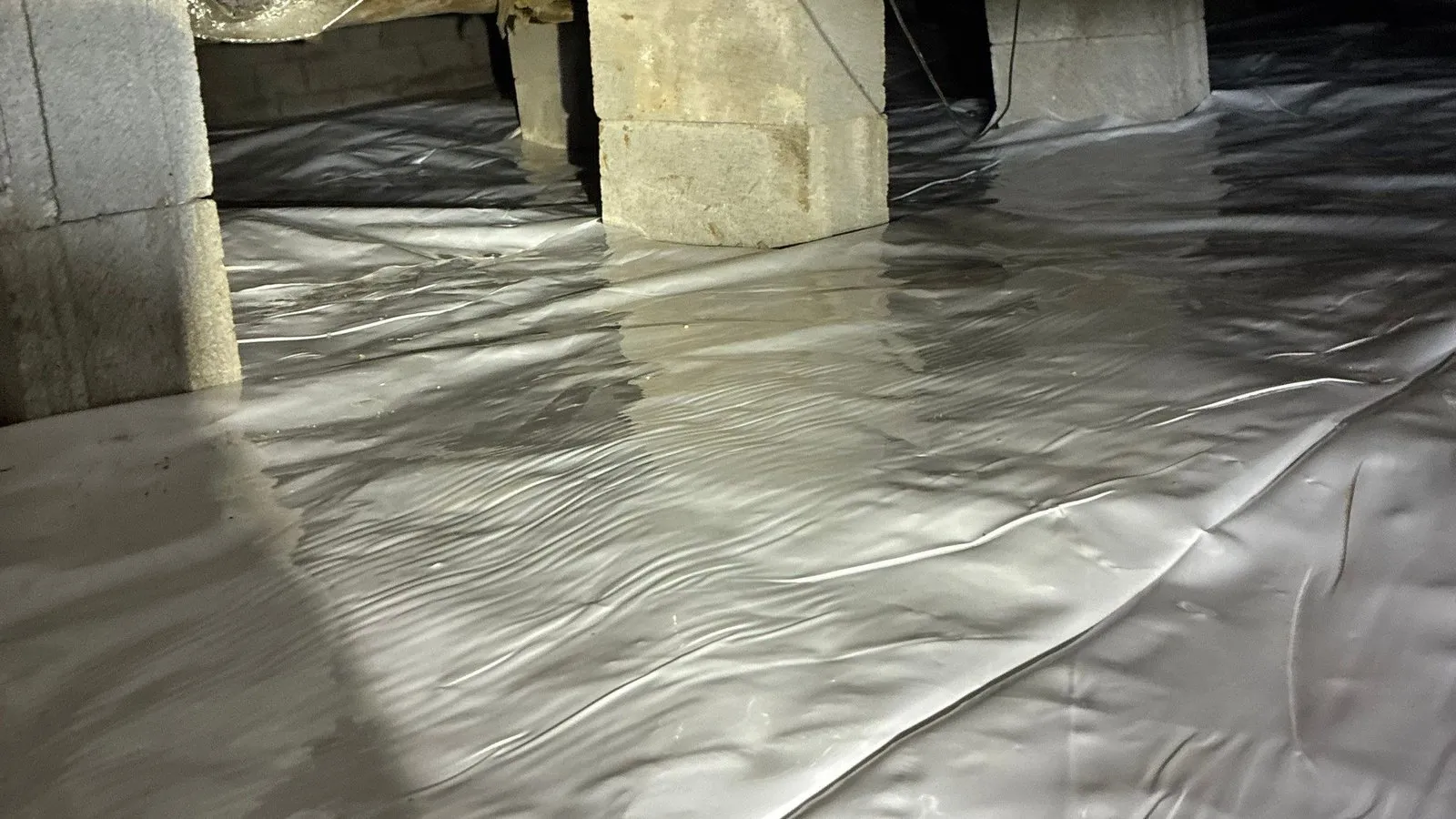 White vapor barrier laid around block piers in a crawlspace