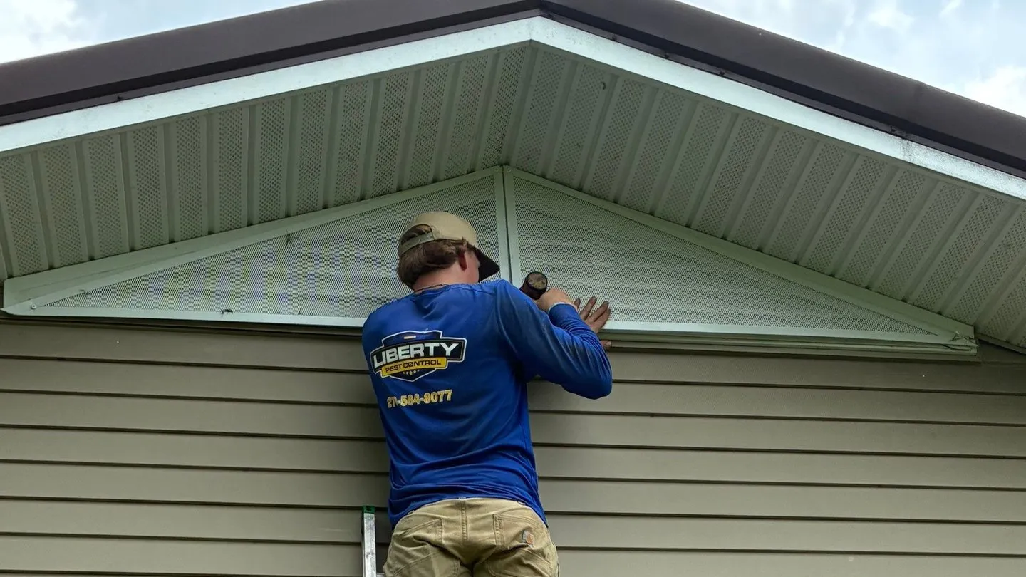 Service Specialist on a ladder installing a guard over a louvered gable vent