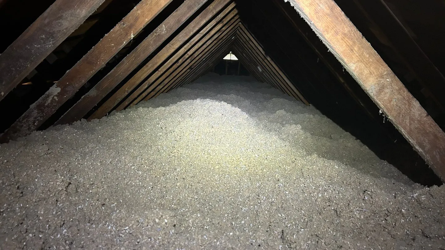Thick blown-in insulation filling an attic floor between the rafters