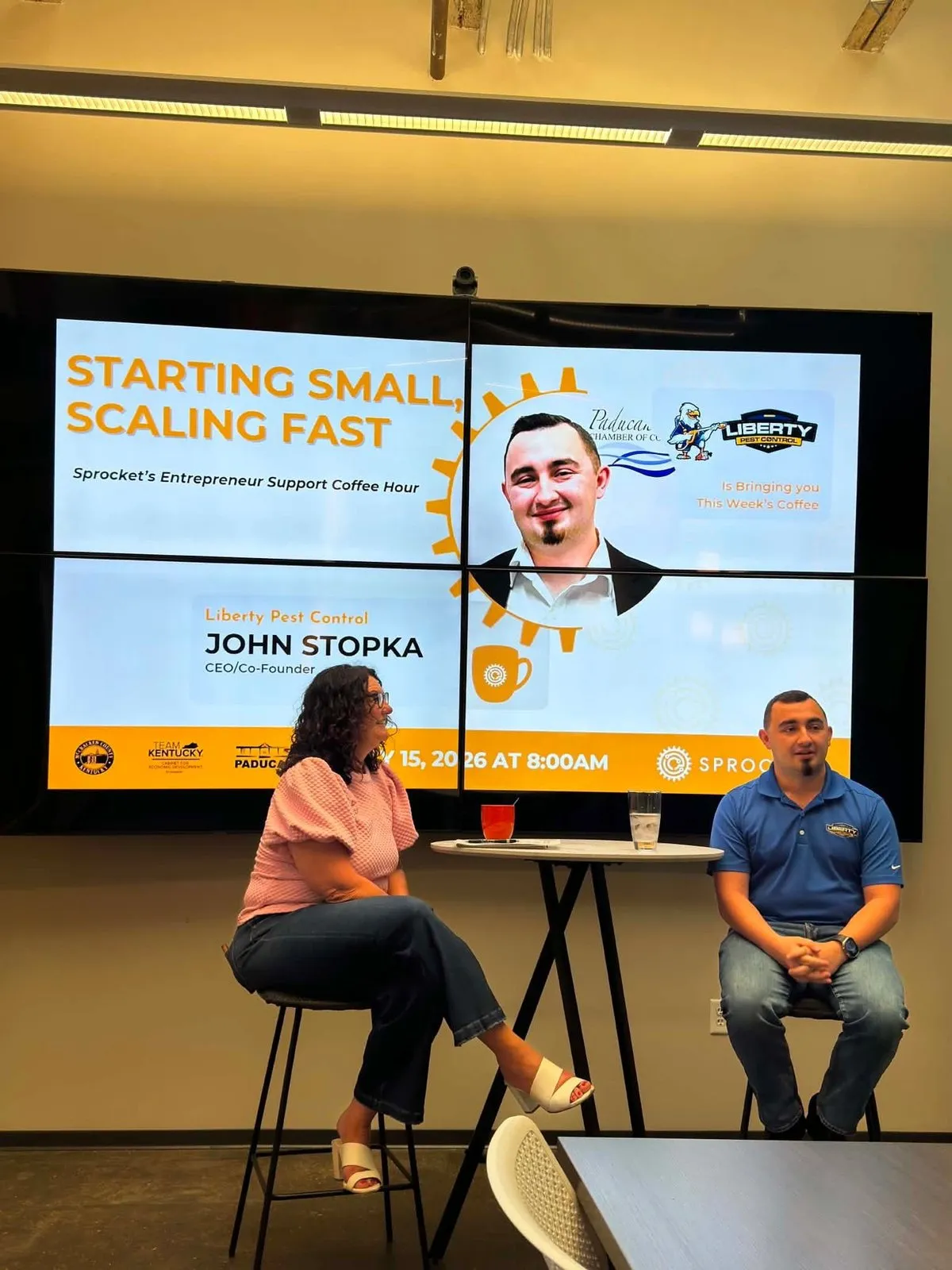 John Stopka on stage at Sprocket Paducah's Entrepreneur Support Coffee Hour, with his name on the screen behind him