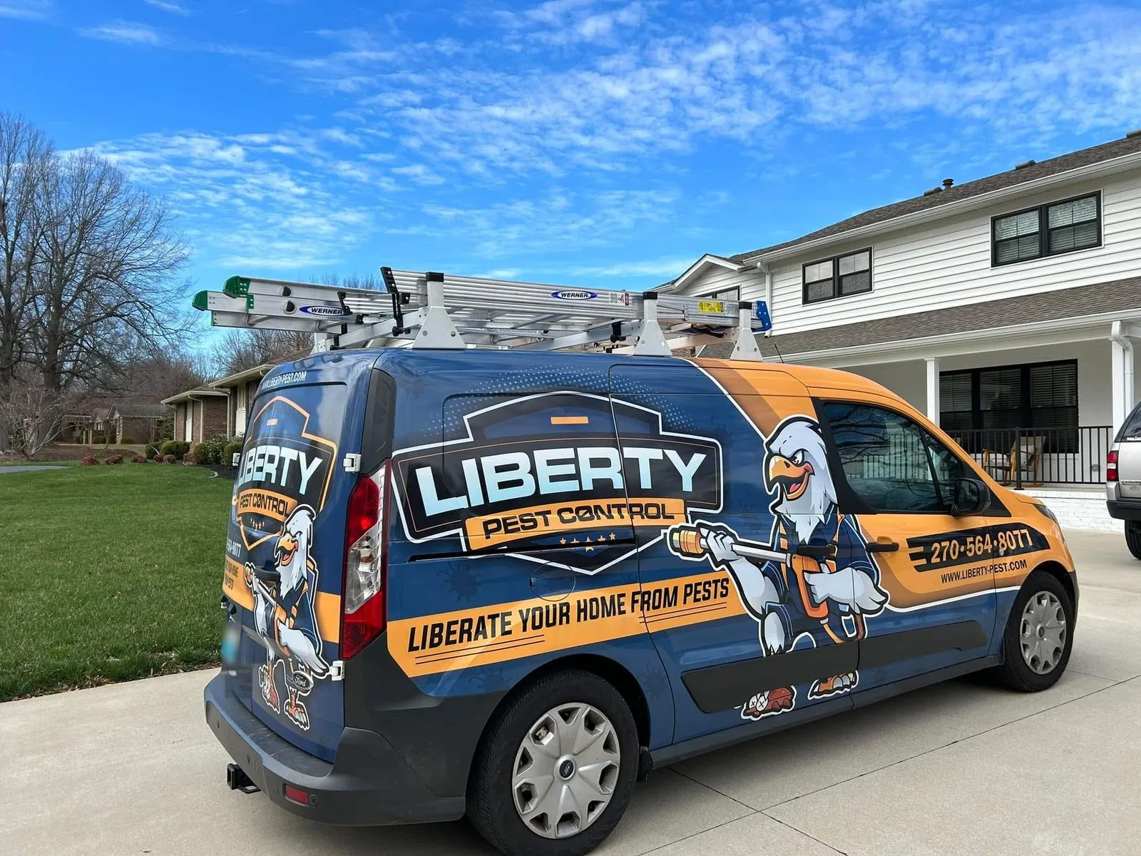 Liberty Pest Control van with ladders on the roof, parked in a home's driveway