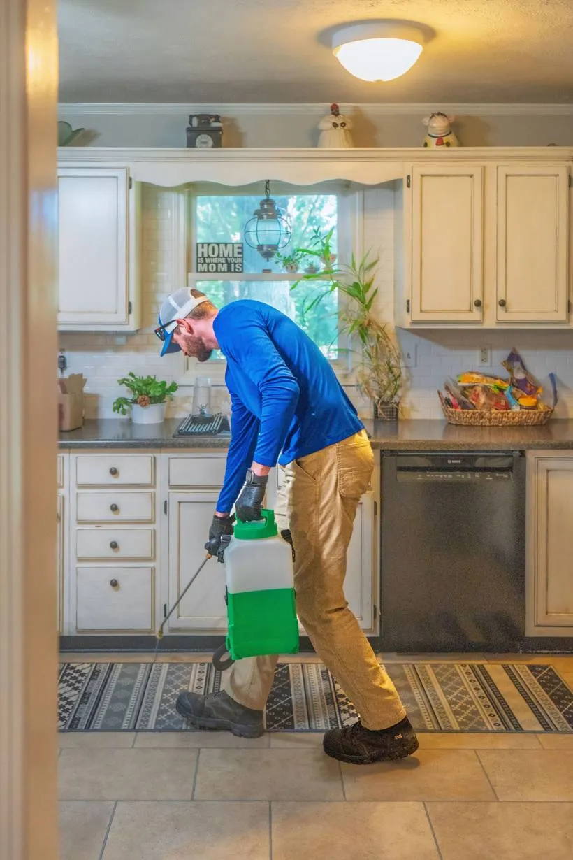 Liberty Service Specialist treating baseboards in a bright home kitchen