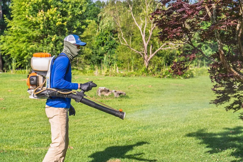 Liberty Service Specialist treating a lawn with a backpack mister